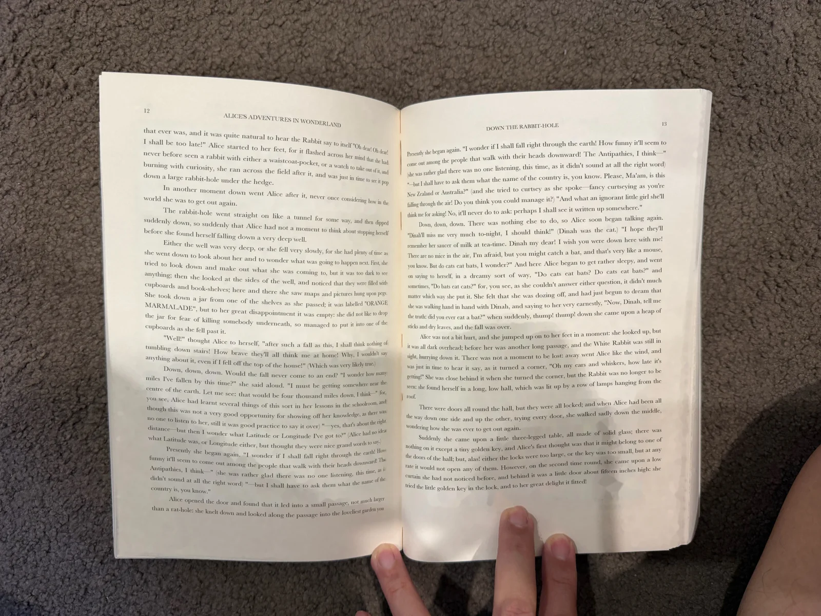 Photo of an open book on a desk: curved pages, a dark spine and fingers holding the pages